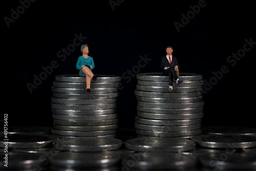Miniature people sitting in the same height pile of coins Macro