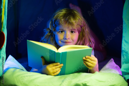 Kids reading books. Towards knowledge. Boy with book read story over dark nigh room background. Child enjoy study and reading book. Book store concept. Wonderful childrens books available to read.