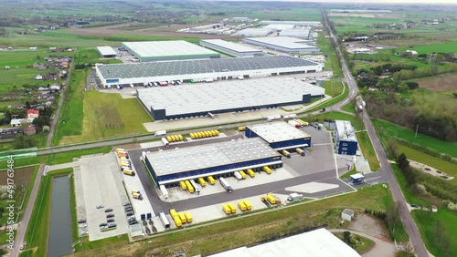 Aerial Shot of Industrial Warehouse Storage Building Loading Area where Many Trucks Are Loading Unloading Merchandise. Shot on Phantom 4K UHD Camera. photo