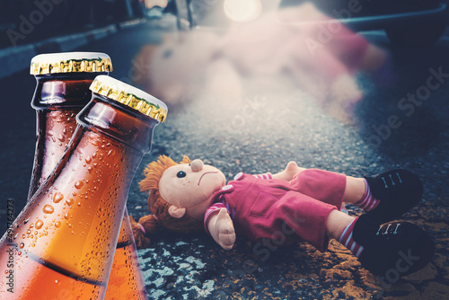 Traffic accident. Close-up of two bottles of beer against the background of a sad doll lying on the road. The concept of drunk driving