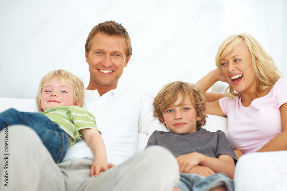 Theyre a young and vibrant family. Happy young family sitting on a sofa together at home.