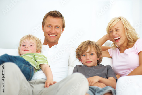 Theyre a young and vibrant family. Happy young family sitting on a sofa together at home.