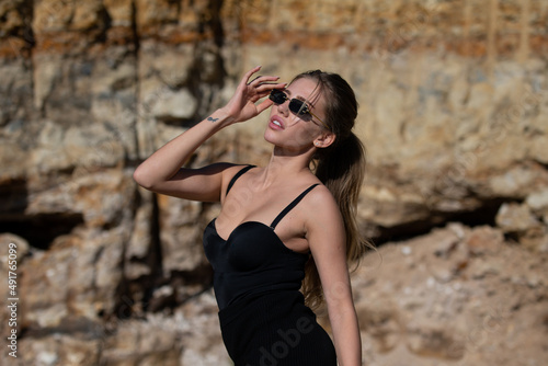Fashion woman in trendy sunglasses and fashion black dress outdoor. © Volodymyr
