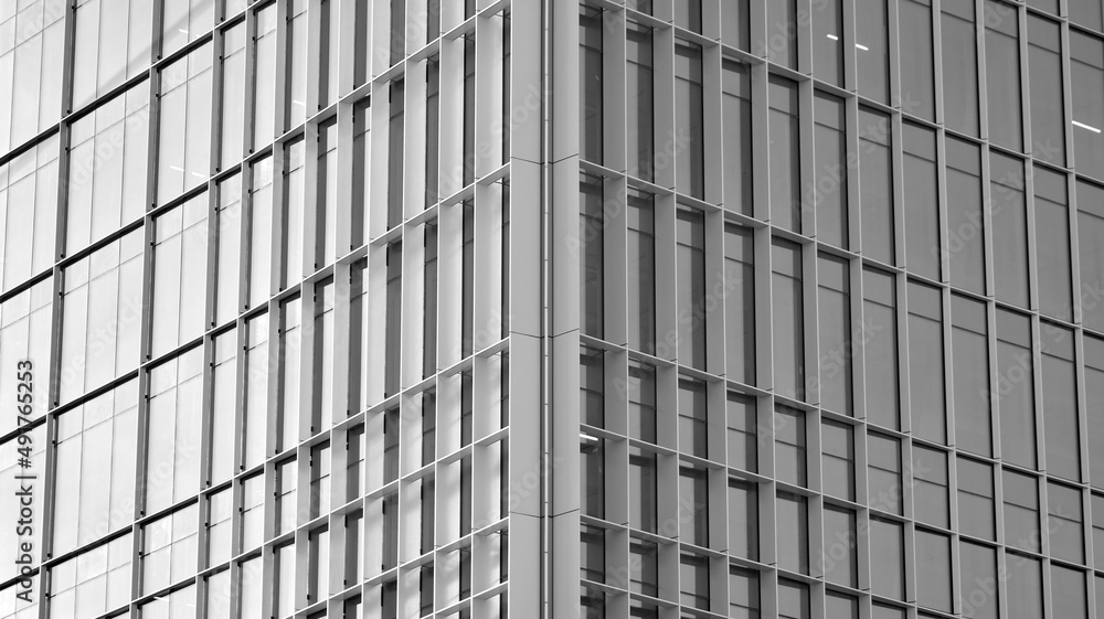Urban abstract - windowed wall of office building. Detail shot of modern business building in city. Looking up at the glass facade of a skyscraper. Black and white filter. Urban abstract - windowed wall of office building. Detail shot of modern business building in city. Looking up at the glass facade of a skyscraper. Black and white filter.