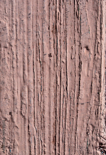 Close-up of a wooden board painted with beige paint as an abstract textural background. A board with peeling, scratched and sun-bleached brown paint. Texture of old painted boards