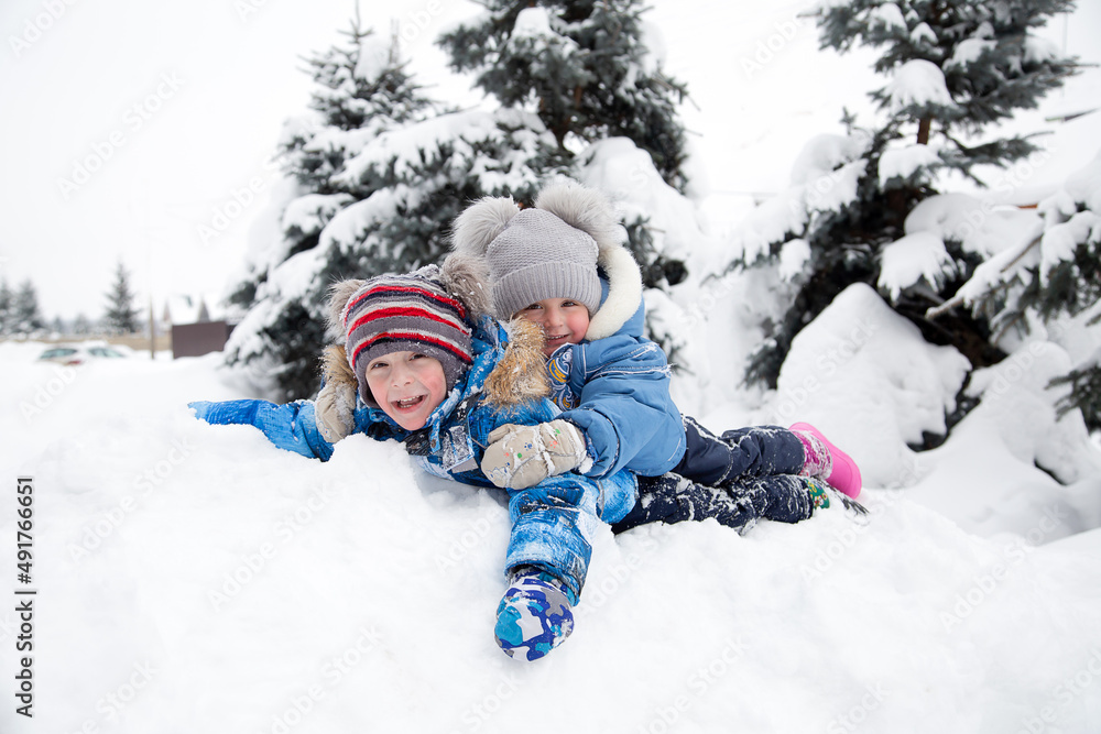 Children play in the snow against the background of snow-covered fir trees Children play in the snow against the background of snow-covered fir trees