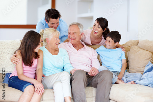 Enjoying grannys joke together. A loving family laughing on a lounge sofa together.
