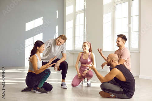 Smiling young people have fun talk chat on break after workout or session in gym. Happy millennial friends team in sportswear speak communicate at training. Sports and physical activity concept.