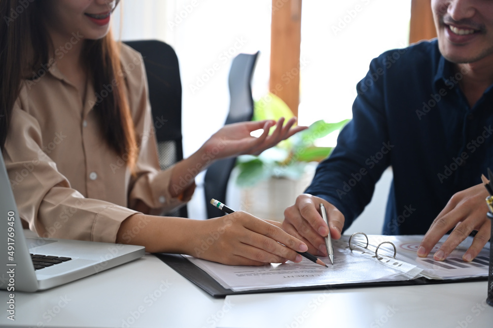 Two young businesspeople having discussion about business report, financial graph at office desk. Two young businesspeople having discussion about business report, financial graph at office desk.