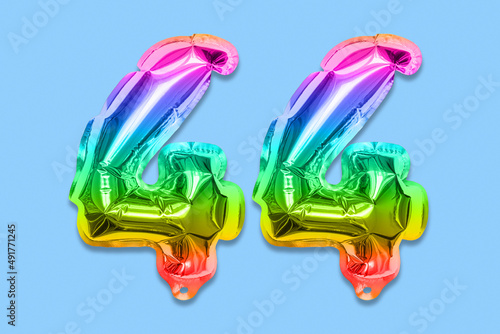Rainbow foil balloon number, digit forty four on a blue background. Birthday greeting card with inscription 44. Top view. Numerical digit. Celebration event, template. photo