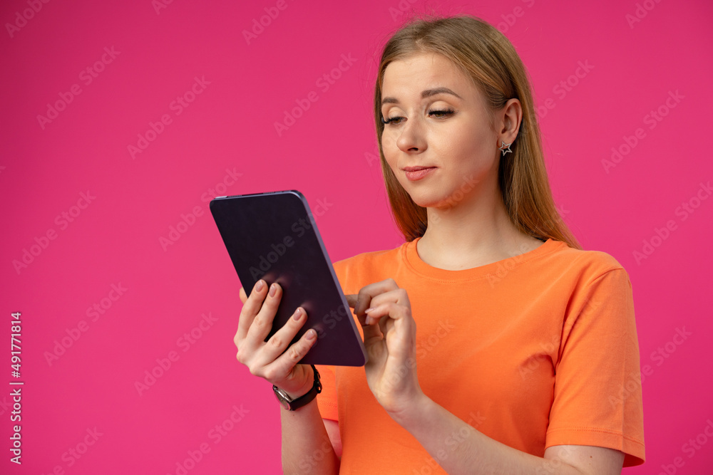 Young woman using digital tablet against pink background