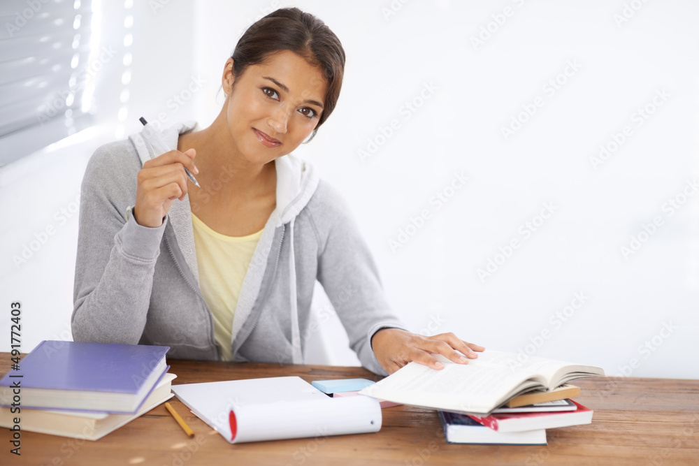 Hitting the books with a positive attitude. A pretty young university student studying for her finals in her dorm room. Hitting the books with a positive attitude. A pretty young university student studying for her finals in her dorm room.