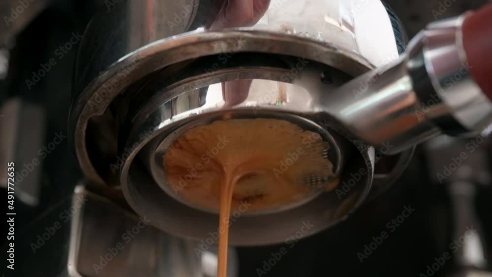 Pouring coffee stream from professional machine in cup. Barista man making espresso shot by bottomless, using filter holder. Flowing fresh ground coffee. Drinking roasted black coffee in the morning Pouring coffee stream from professional machine in cup. Barista man making espresso shot by bottomless, using filter holder. Flowing fresh ground coffee. Drinking roasted black coffee in the morning