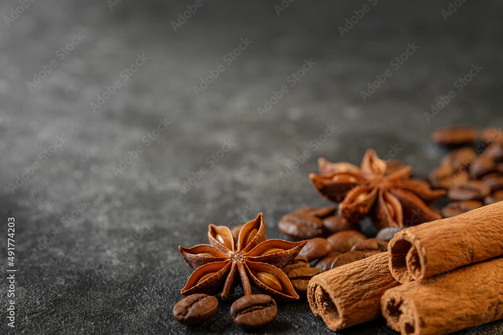 Cinnamon sticks, anise stars and coffee beans on dark grey background. Copy space