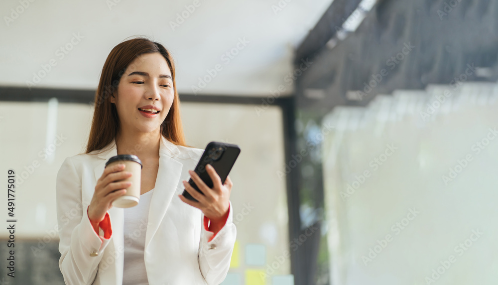 Asian business woman in cafe using mobile phone. Girl chatting on smartphone and drinking coffee in restaurant near window, smiling at cellphone screen. Asian business woman in cafe using mobile phone. Girl chatting on smartphone and drinking coffee in restaurant near window, smiling at cellphone screen.