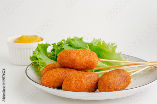 Traditional American fast food. Corn dogs on white background with mustard. Copy space