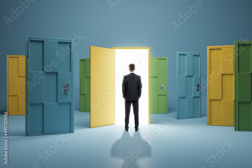 Man standing in front of abstract colorful puzzle door in interior. Future, choice, success, direction, opportunity and solution concept.