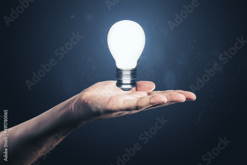Close up of male hand holding glowing light bulb. Idea and innovation concept. photo