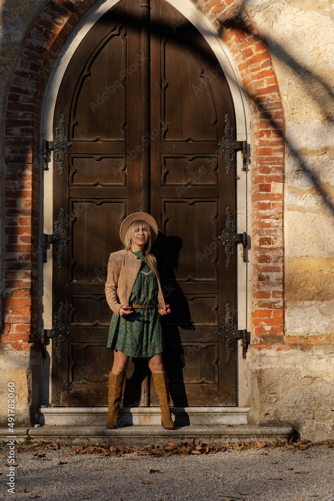 photo of girl in the boho style on background of gate of chapel of Middle Ages
