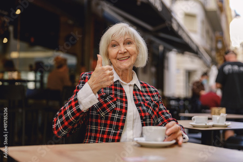 Positive pensioner female having coffee at cafe