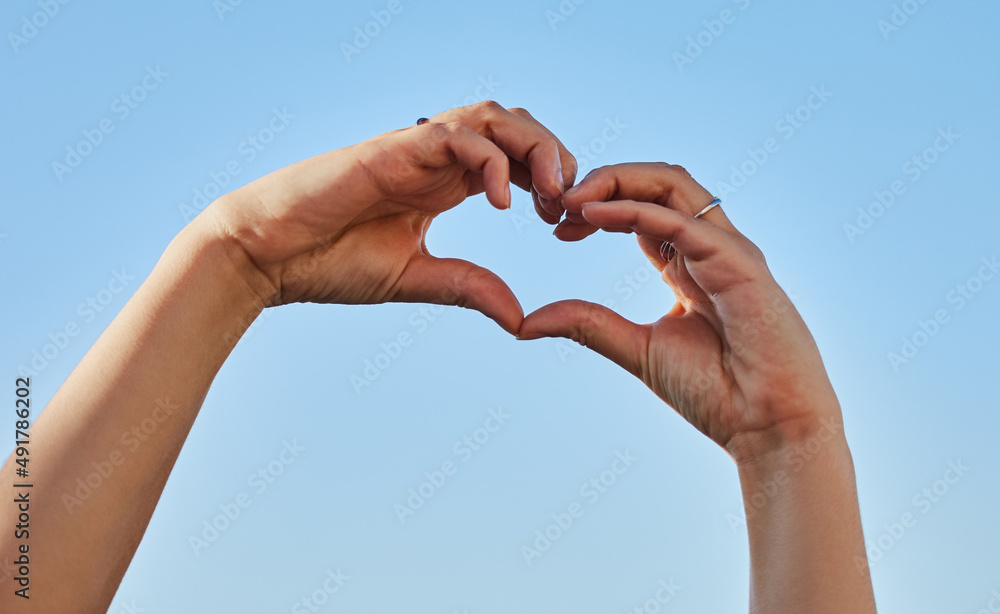 Give a little and youll receive a lot. Cropped shot of a woman forming a heart shape with her hands against a blue sky. Give a little and youll receive a lot. Cropped shot of a woman forming a heart shape with her hands against a blue sky.