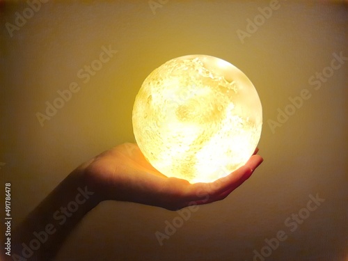 Male hand holding a yellow full moon.