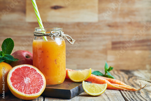 Fruit juice served in jar. Various fresh fruit juice citrus apple and carrots served in jar on wooden table. Fruit healthy juice for detox.