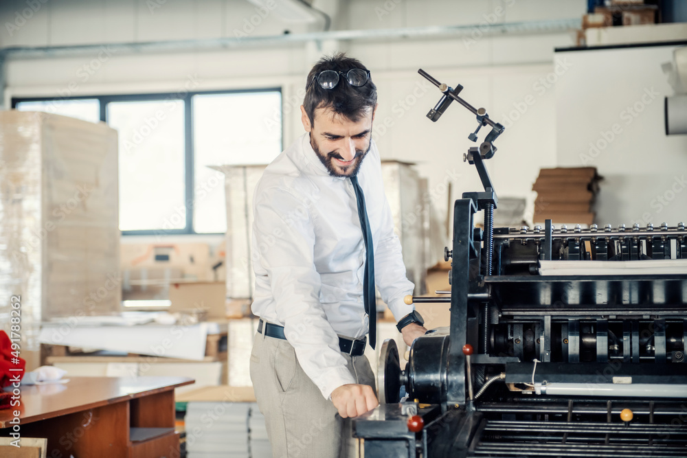 A graphic engineer adjusting printing machine at printing shop. A graphic engineer adjusting printing machine at printing shop.