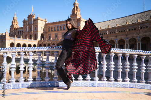 Young and beautiful woman dancing flamenco and Spanish posing in urban clothes, wearing her hair loose and long and standing on the tips of her shoes. flamenco cultural heritage of humanity.