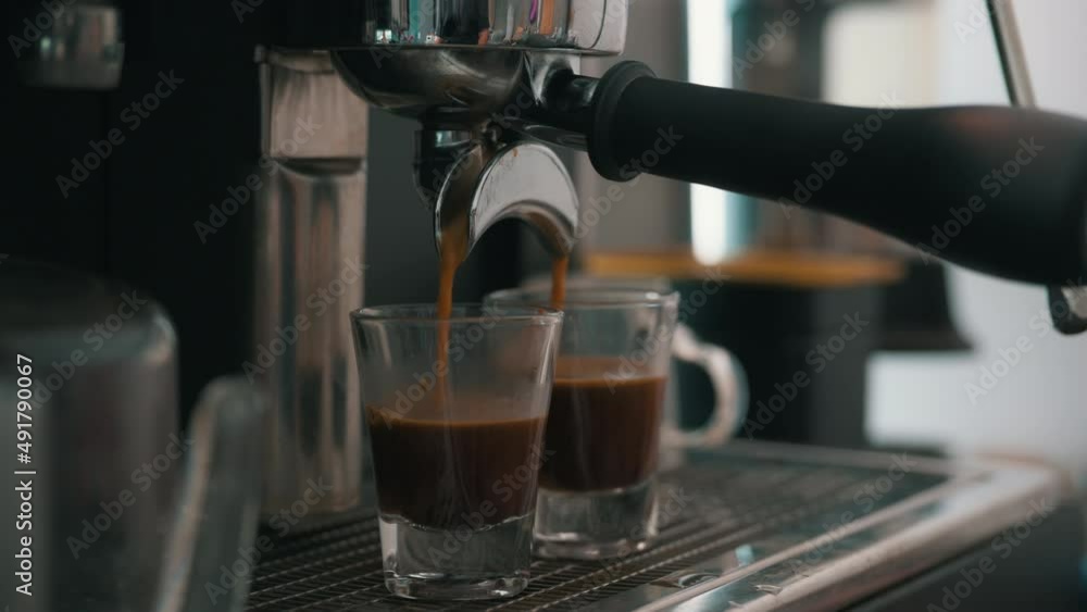 Pouring coffee stream from professional machine in cup. Barista man making espresso shot by bottomless, using filter holder. Flowing fresh ground coffee. Drinking roasted black coffee in the morning Pouring coffee stream from professional machine in cup. Barista man making espresso shot by bottomless, using filter holder. Flowing fresh ground coffee. Drinking roasted black coffee in the morning