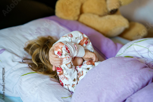 Cute little preschhol girl after sleeping in bed. Happy joyful smiling child wake up in the morning, healthy sleep of children by day photo