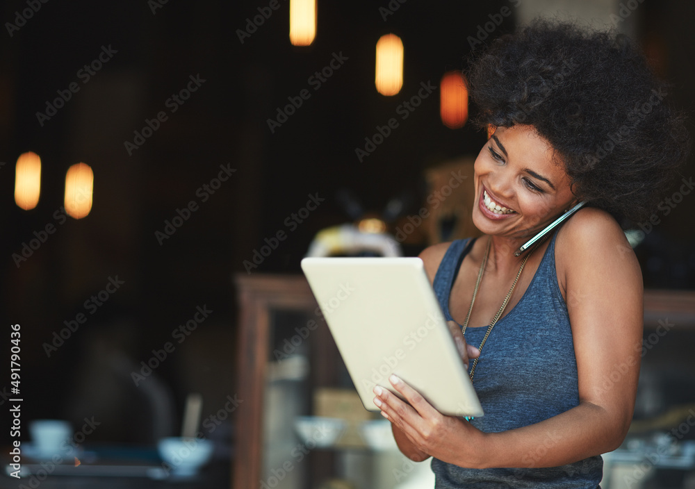 Success is the order of the day. Shot of a young woman using a digital tablet while talking on the phone at a cafe. Success is the order of the day. Shot of a young woman using a digital tablet while talking on the phone at a cafe.
