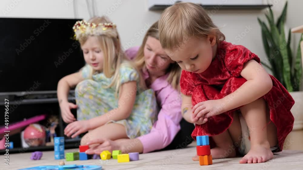 Happy mother or nanny playing with child and building towers from colorful blocks construction bricks, having fun, enjoying leisure, creative game together. Educational toy. Selective focus Happy mother or nanny playing with child and building towers from colorful blocks construction bricks, having fun, enjoying leisure, creative game together. Educational toy. Selective focus