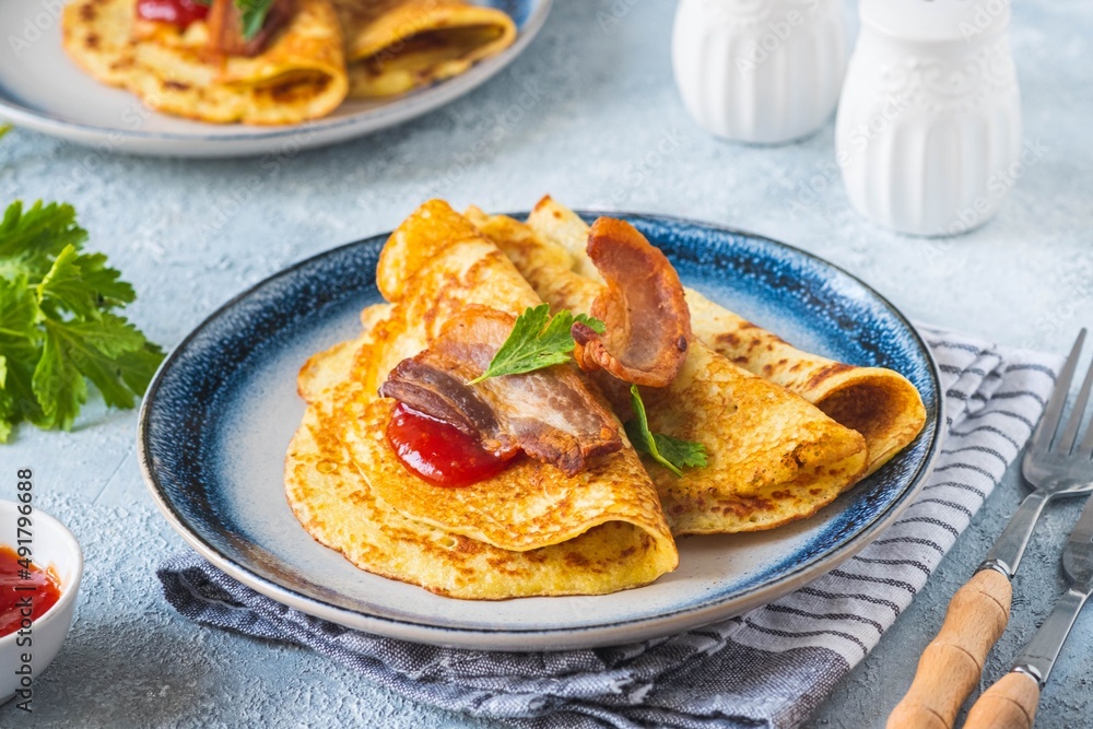 Swedish Ragmunk potato pancakes with fried bacon and berry sauce on a ceramic plate on a gray concrete background. Swedish cuisine. Swedish Ragmunk potato pancakes with fried bacon and berry sauce on a ceramic plate on a gray concrete background. Swedish cuisine.