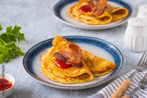 Swedish Ragmunk potato pancakes with fried bacon and berry sauce on a ceramic plate on a gray concrete background. Swedish cuisine. photo