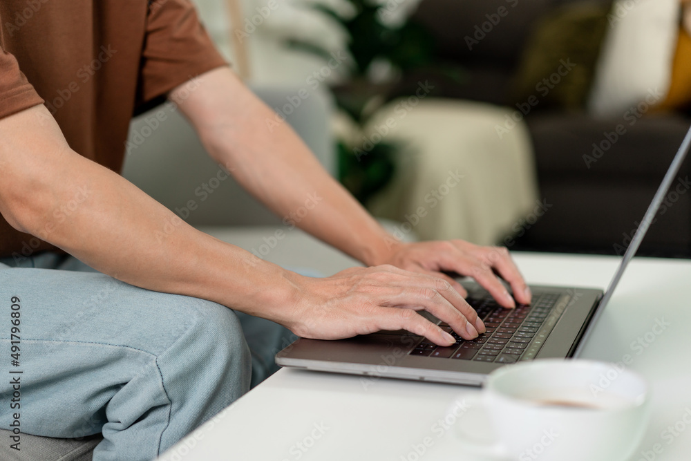 Technology Concept The man in brown T-shirt concentrating on typing something on his computer laptop Technology Concept The man in brown T-shirt concentrating on typing something on his computer laptop