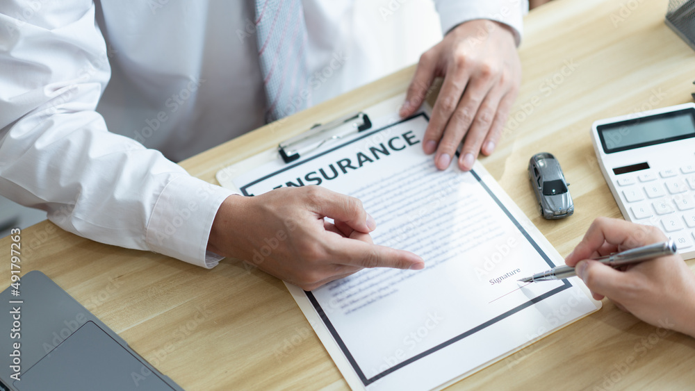 Insurance concept the male dealer suggesting his customer to sign the contract of car purchasing Insurance concept the male dealer suggesting his customer to sign the contract of car purchasing