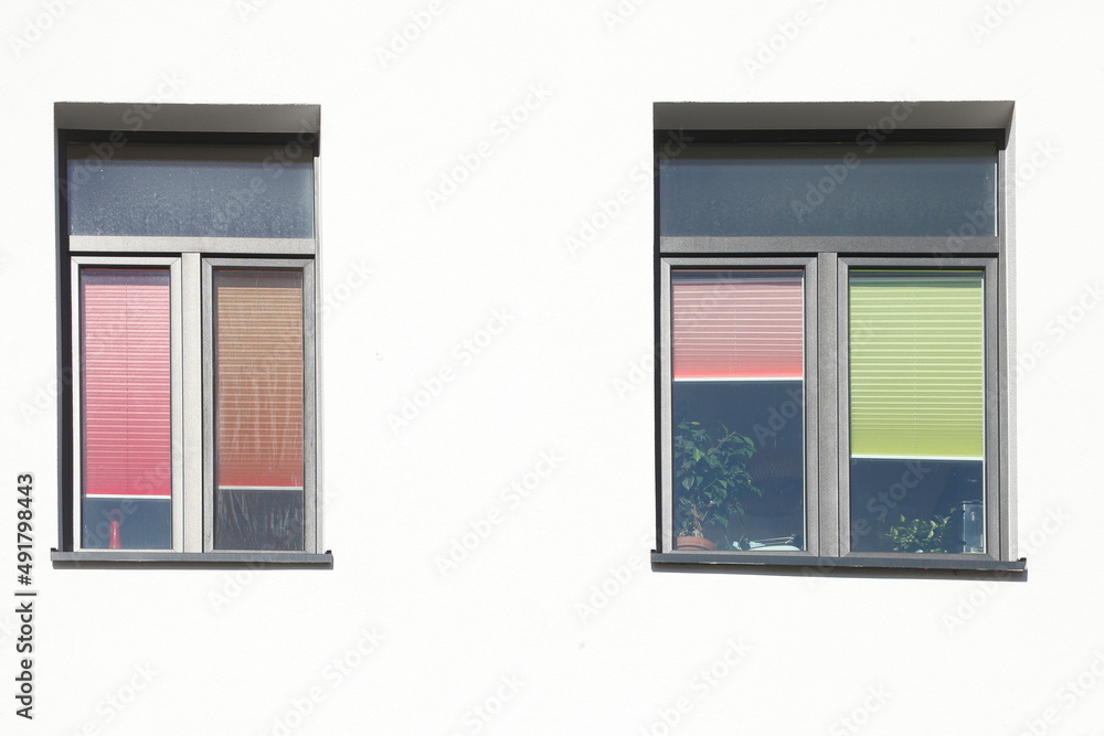 Fenster mit bunten heruntergezogenen Rolläden an einer weißen Hauswand, Deutschland, Europa