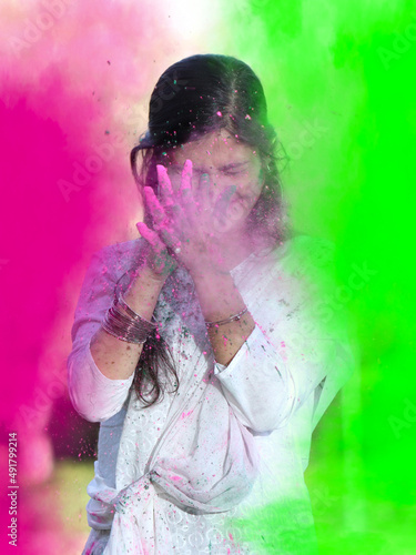Portrait of happy Indian girl celebrating Holi with powder colours or gulal. Concept of Indian festival Holi.