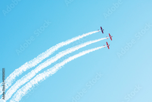 Three light engine airplane flying in a cloud of smoke in the blue sky.
