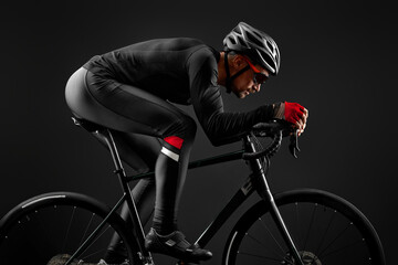 male cyclist riding road bicycle on black background