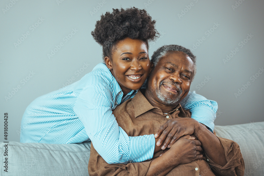 Adult daughter visits senior father in assisted living home. Portrait of a daughter holding her elderly father, sitting on a bed by a window in her father's room. Adult daughter visits senior father in assisted living home. Portrait of a daughter holding her elderly father, sitting on a bed by a window in her father's room.