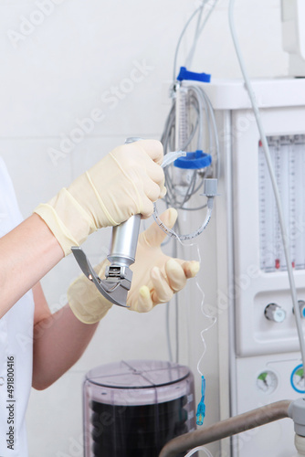 Preparation for surgery under general anesthesia. Tracheal intubation. Laryngoscope for emergency medicine. The doctor s hands are in protective gloves. Modern medicine. Vertical photo.