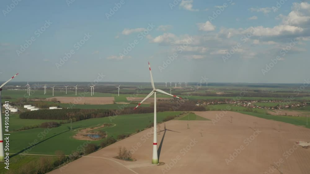 Rotating rotor with striped ends of blades. Aerial view of wind turbines in flat countryside. Green energy, ecology and carbon footprint reduction concept Rotating rotor with striped ends of blades. Aerial view of wind turbines in flat countryside. Green energy, ecology and carbon footprint reduction concept