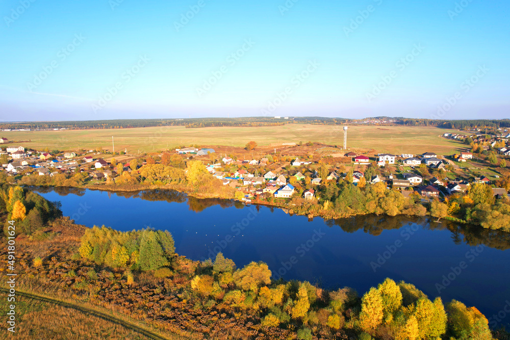 Country houses at river in countryside, aerial view. Building a Home in the Country. Village with wooden house. Suburban house in rural on sunset. Rural building and farmhouse at lake in countryside.