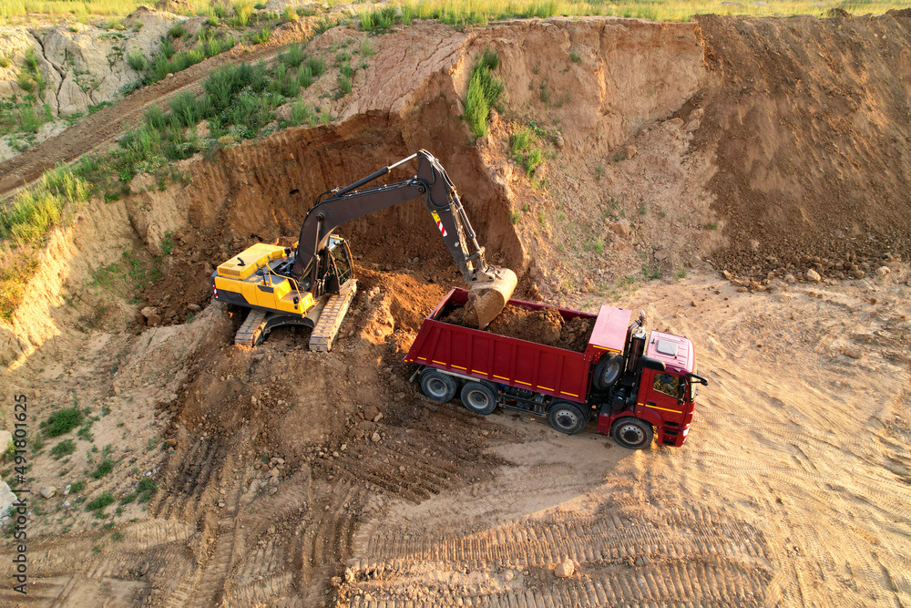 Earthmoving at construction site. Excavator load soil in dump truck. Excavator on earthworks. Open pit development and sand mining. Loader digg ground for foundation pit. Earthmover and digger.. Earthmoving at construction site. Excavator load soil in dump truck. Excavator on earthworks. Open pit development and sand mining. Loader digg ground for foundation pit. Earthmover and digger..