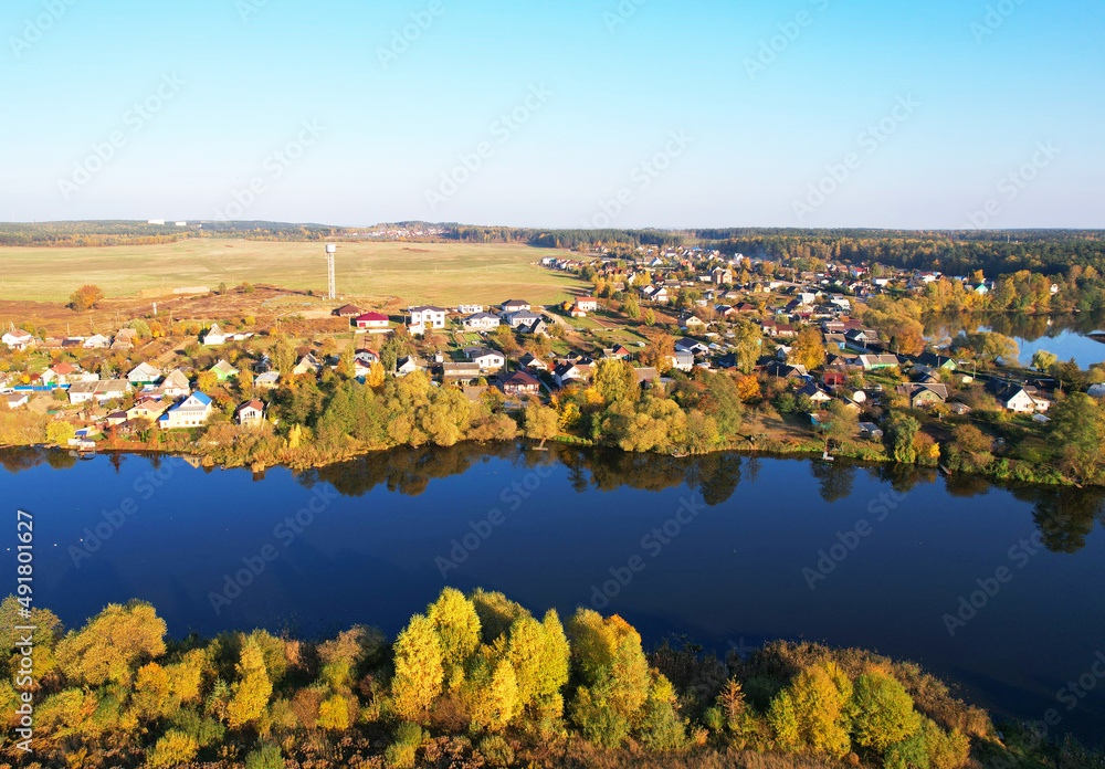 Country houses at river in countryside, aerial view. Building a Home in the Country. Village with wooden house. Suburban house in rural on sunset. Rural building and farmhouse at lake in countryside.