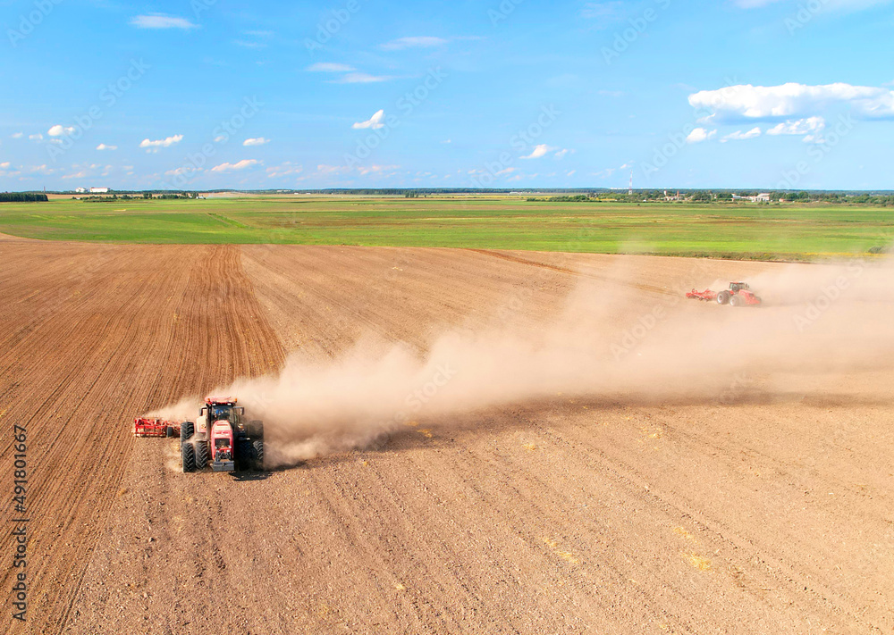 Obraz premium Cultivated land and soil tillage. Tractor with disc cultivator on land cultivating. Agricultural tractor on cultivation field. Tractor disk harrow on plowing field. Soil cultivation, Plough plowed.
