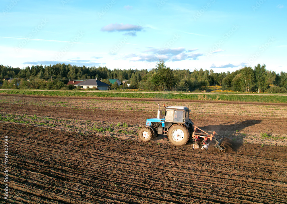 Obraz premium Cultivated land and soil tillage. Tractor with disc cultivator on land cultivating. Agricultural tractor on cultivation field. Tractor disk harrow on plowing field. Soil cultivation, Plough plowed.