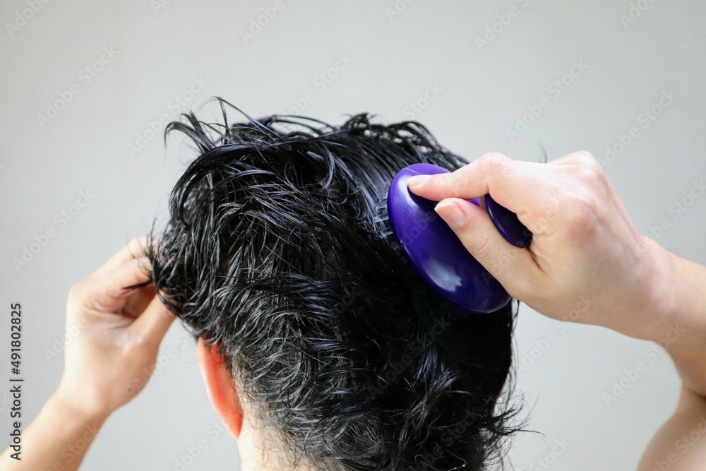 Naklejka premium ヘアブラシで頭皮をマッサージする日本人男性